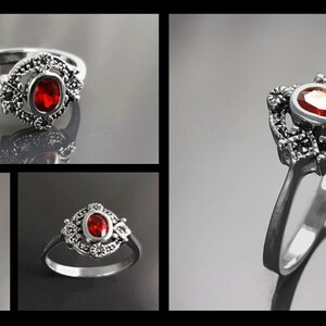 K&ouml;nnte beinhalten: Silberner Ring mit einem ovalen, roten Edelstein im Zentrum. Der Edelstein ist von einer dekorativen, bl&uuml;tenartigen Fassung umgeben. Der Ring wird in verschiedenen Ansichten pr&auml;sentiert, um sein Design hervorzuheben.