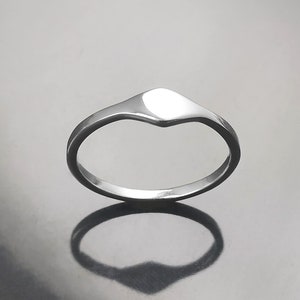 May include: A simple silver ring with a flat, rounded top. The ring is smooth and polished.