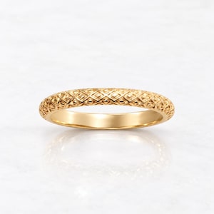May include: A gold ring featuring a continuous, raised diamond-shaped lattice pattern across its outer surface. The band has a polished, smooth interior and a rounded profile, showcasing a consistent metallic yellow finish throughout the design.