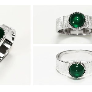 Puede incluir: Un anillo de plata con una banda texturizada y una piedra preciosa verde engastada en un engaste de plata.