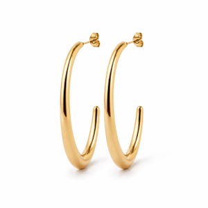 Peut inclure: Une paire de boucles d'oreilles créoles dorées. Les boucles d'oreilles ont une finition lisse et polie et un design classique et minimaliste. Les créoles sont de taille moyenne et comportent une fermeture à tige et à poussette.