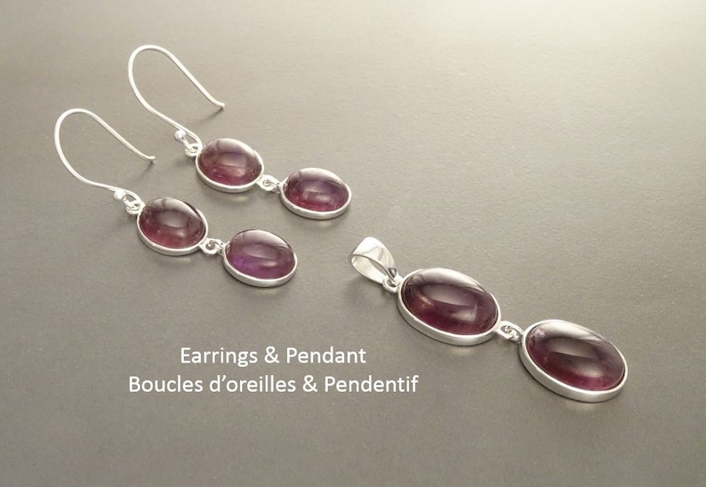 May include: A jewelry set featuring a pair of earrings and a pendant. Each piece has a silver setting and features two oval, deep purple gemstones. The text "Earrings & Pendant" is visible.