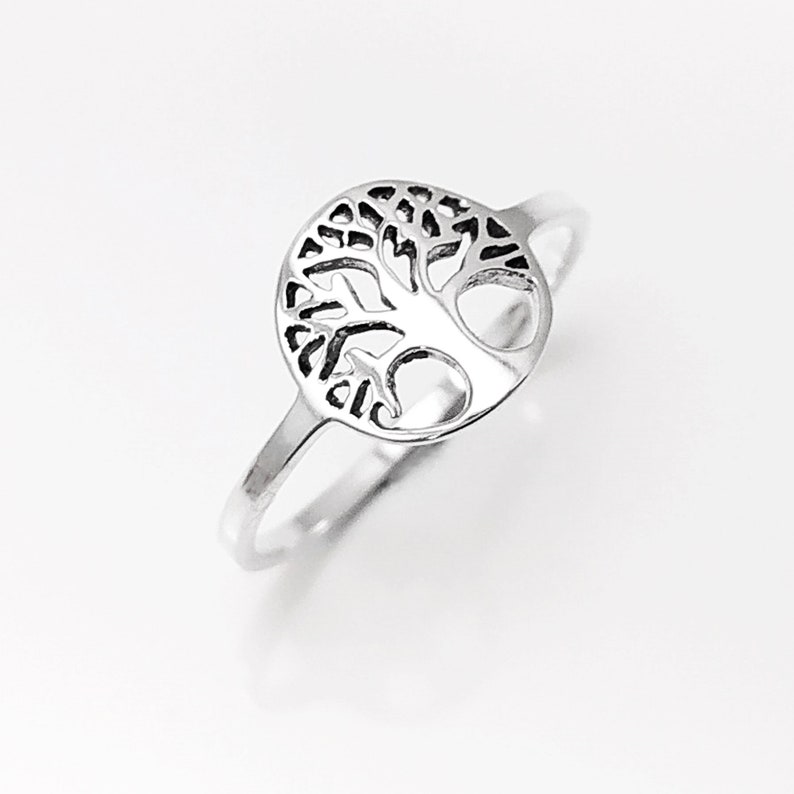 May include: A silver ring featuring a tree of life design. The ring is simple and elegant, and the tree of life is a popular symbol of growth, strength, and resilience.
