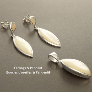 May include: A jewelry set consisting of two drop earrings and one pendant. Each piece features a marquise-shaped white mother-of-pearl inlay set in a polished silver frame. The earrings have a small teardrop accent and post-style backs.