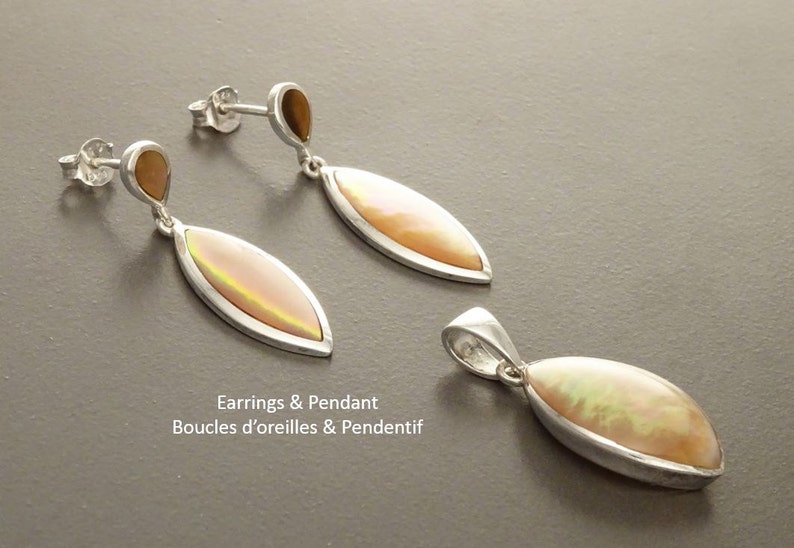 May include: A pair of silver drop earrings and a matching pendant, each featuring a marquise-shaped iridescent stone. The earrings have a small teardrop-shaped accent at the top. The text "Earrings & Pendant" is visible in the image.