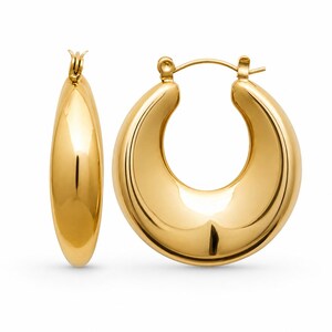 May include: A pair of gold-coloured hoop earrings. The earrings have a rounded, thick design and a polished finish. The hoops are a classic jewellery style, suitable for various occasions.