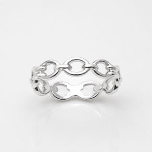 May include: A polished silver ring featuring a continuous chain-link design. The band is composed of interconnected oval-shaped metal links that create an openwork pattern, showcasing a bright, reflective metallic finish throughout the entire piece.