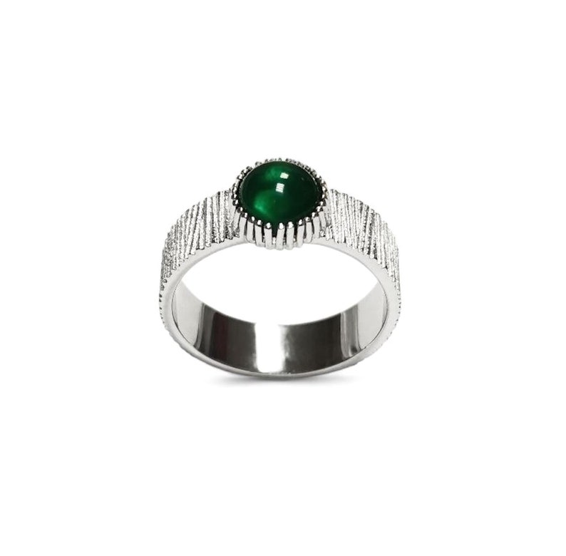 Puede incluir: Un anillo de plata con una banda texturizada y una piedra preciosa verde engastada en un engaste de plata.