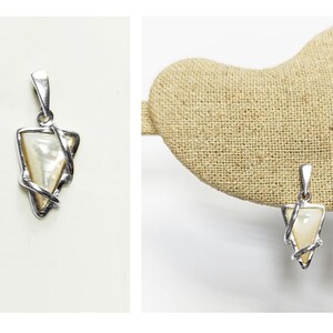 May include: A pair of silver-toned pendants featuring a triangular-shaped iridescent mother-of-pearl inlay. Each pendant is encased in a polished silver-toned metal frame that wraps around the edges of the triangle, topped with a silver-toned bail.