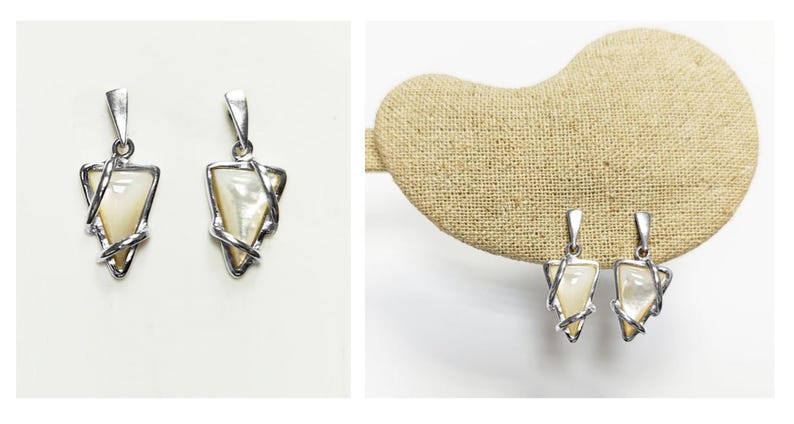 May include: A pair of silver-toned pendants featuring a triangular-shaped iridescent mother-of-pearl inlay. Each pendant is encased in a polished silver-toned metal frame that wraps around the edges of the triangle, topped with a silver-toned bail.