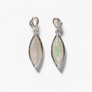 May include: A pair of drop earrings featuring silver-toned metal settings. Each earring consists of a small, teardrop-shaped iridescent stone at the top, connected by a jump ring to a larger, elongated marquise-shaped iridescent stone below.