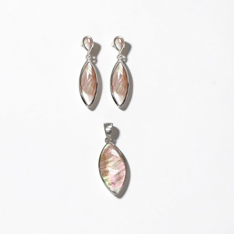 May include: A jewelry set consisting of two drop earrings and one matching pendant. Each piece features a marquise-shaped iridescent shell inlay set in a polished silver-tone metal frame. The earrings have a small circular top connector.