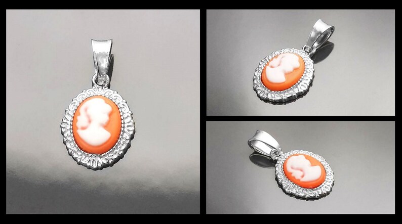 May include: A silver pendant with a cameo featuring a white profile of a person on an orange background. The cameo is surrounded by a silver filigree design.