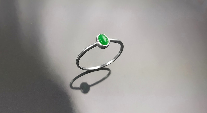 May include: A silver ring with a green oval-shaped gemstone.