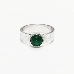 Puede incluir: Un anillo de plata con una banda texturizada y una piedra preciosa verde engastada en un engaste de plata.
