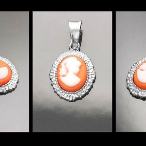 May include: A silver pendant with an oval cameo featuring a white silhouette of a woman's profile on an orange background.