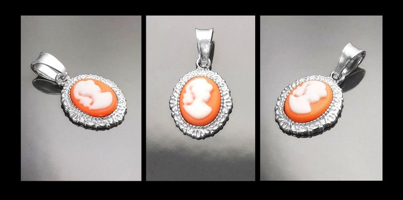 May include: A silver pendant with an oval cameo featuring a white silhouette of a woman's profile on an orange background.