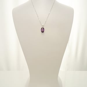 May include: A silver chain necklace with a purple oval pendant.