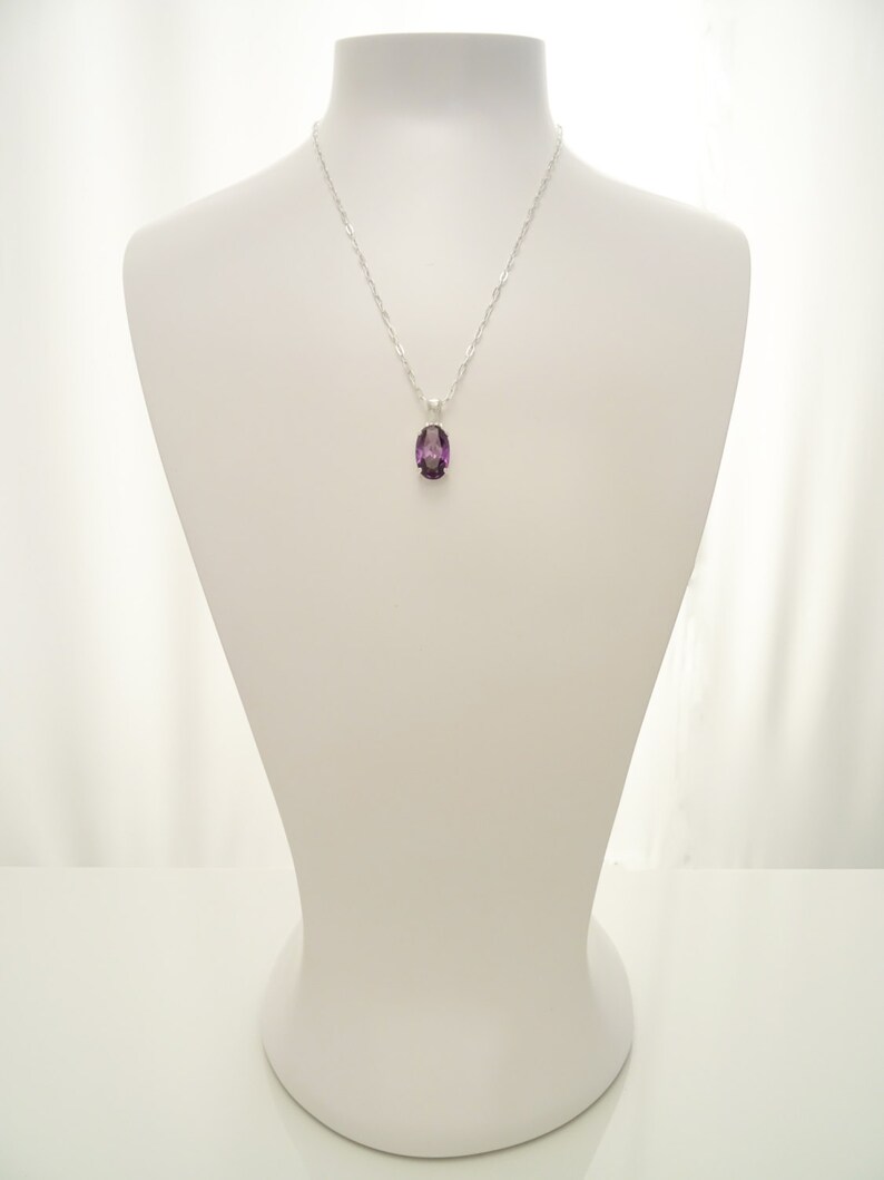 May include: A silver chain necklace with a purple oval pendant.