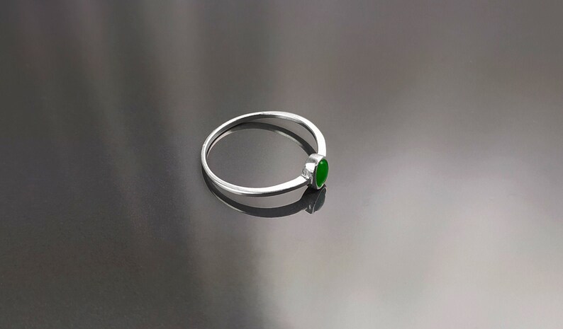 May include: A silver ring with a green oval-shaped gemstone.
