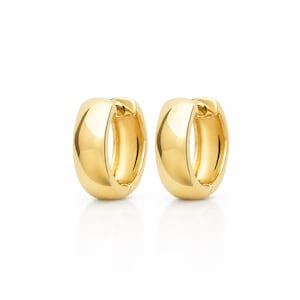 Könnte beinhalten: Ein Paar polierte Gold-Creolen mit einem dicken, abgerundeten Profil und einem Klappverschluss. Die Ohrringe haben eine glatte, reflektierende Oberfläche, die das Licht einfängt und ein schlichtes, kreisförmiges Design mit sicherem Verschluss zeigt.