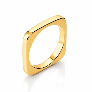 Peut inclure: Une bague dorée de forme carrée aux coins arrondis. La bague est faite d'un matériau brillant et réfléchissant, sur fond blanc. Le design de la bague est minimaliste et moderne.