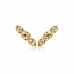 May include: A pair of gold-colored ear climbers with an ornate design. Each climber features three turquoise-colored stones and one dark blue stone, set within a detailed, dotted pattern. The earrings are displayed on a white background.