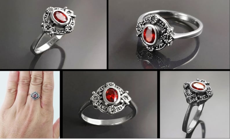 K&ouml;nnte beinhalten: Ein silberner Ring mit einem ovalen, roten Edelstein in der Mitte, umgeben von einem dekorativen floralen Design. Der Ring wird aus verschiedenen Blickwinkeln gezeigt, um seine komplizierten Details hervorzuheben. Auf einem Foto wird der Ring an einer Hand getragen.