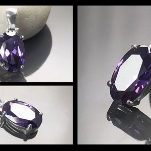 May include: A silver pendant with a large, faceted, oval-shaped purple gemstone.