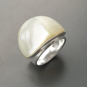 May include: A white ring with a gold band and a large, white, oval-shaped stone.