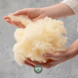 Puede incluir: Una taza de cerámica blanca con un asa negra y el texto "But First, Coffee" en negrita negra. La taza está sobre un fondo borroso. La taza mide aproximadamente 10 cm de altura.