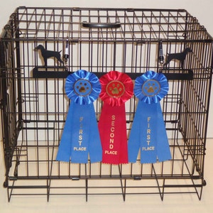 May include: A black metal dog crate with three ribbons hanging from the top. The ribbons are blue, red, and blue, and they say "First Place" and "Second Place".