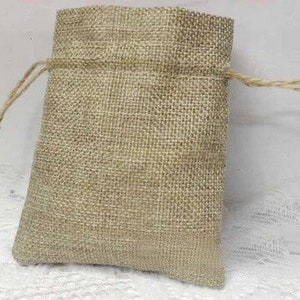 K&ouml;nnte beinhalten: Eine kleine, nat&uuml;rliche Jutesack mit einem hellbraunen Farbton. Die Tasche ist aus einem gewebten Stoff gefertigt und hat ein schlichtes Design.