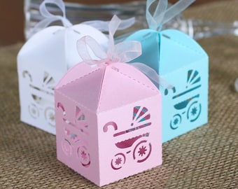 May include: Three small, decorative gift boxes with cut-out designs of baby carriages. The boxes are white, pink, and blue.