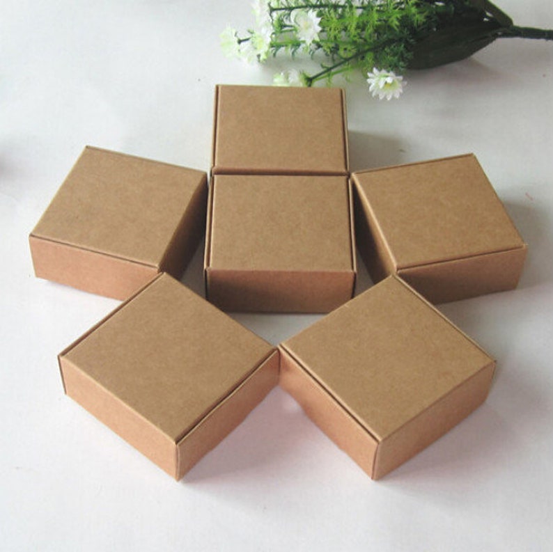 May include: Six brown cardboard boxes of various sizes, arranged in a star shape on a white surface.