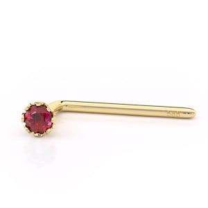May include: A gold nose ring with a red gemstone. The ring is marked with "585", indicating it is 14 karat gold.