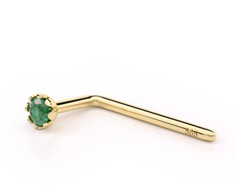 May include: Gold nose ring with a green emerald gemstone. The ring is bent at a 90-degree angle.