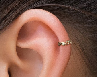 May include: Gold ear cuff with a delicate chain design and small round accents. The cuff is worn in the upper ear cartilage.