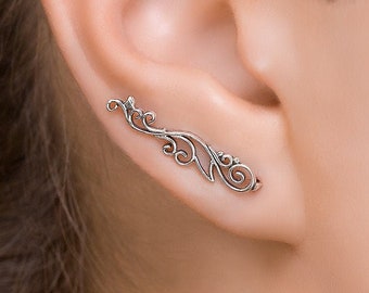 May include: Silver ear cuff with a delicate, intricate floral design. The cuff is curved and designed to fit along the upper edge of the ear.