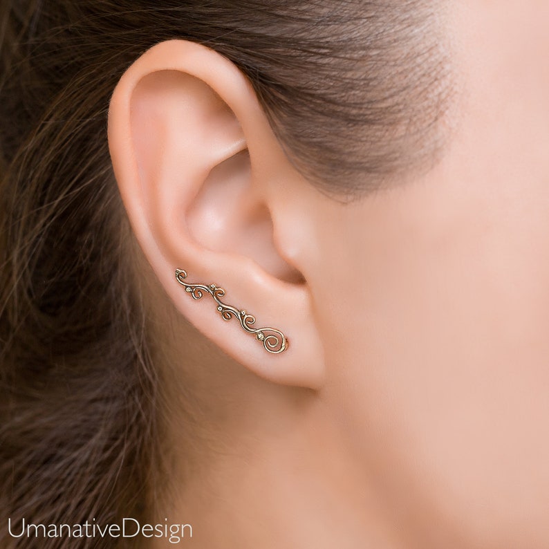 May include: A gold ear cuff with a delicate, vine-like design. The cuff is made of metal and has a subtle shine.
