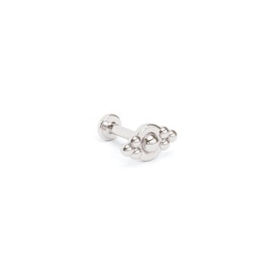 May include: Silver body jewelry with a cluster of small balls on a circular base.