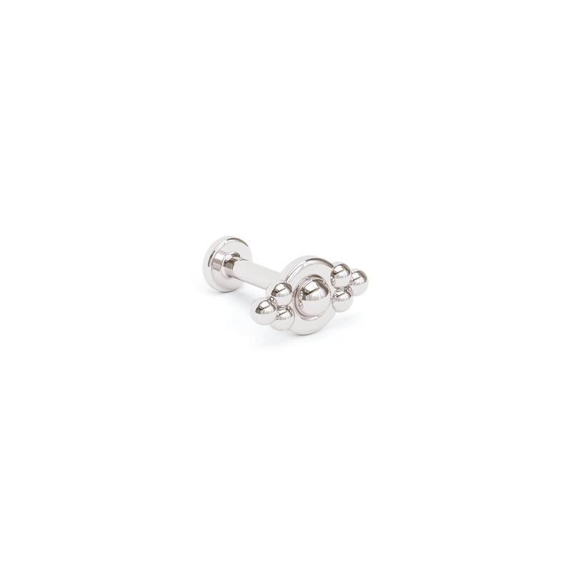 May include: Silver body jewelry with a cluster of small balls on a circular base.