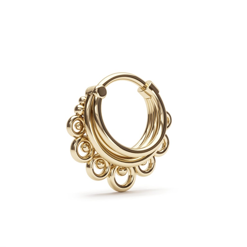 May include: Gold hoop earrings with a decorative design of multiple circles and beads.