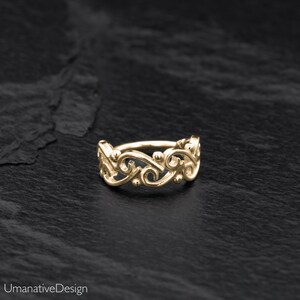 May include: Gold nose ring with a delicate, ornate design featuring a series of connected swirls and dots.