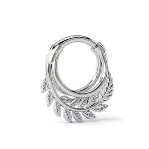 May include: A silver-colored, hinged hoop earring with a leaf design. The earring features a circular shape with a series of leaves on the lower portion. The leaves are detailed with visible veins, adding texture to the design. The earring is made of a shiny, metallic material.