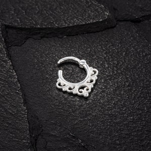 K&ouml;nnte beinhalten: Silberner Nasenring mit einem zarten, verzierten Design. Der Ring ist rund mit einem dekorativen Filigranmuster.