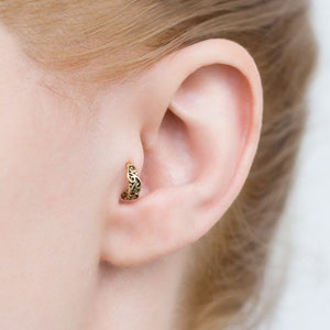 May include: Gold filigree ear cuff with a delicate design. The cuff is worn in the upper ear, near the helix.