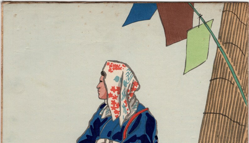 May include: A woman wearing a blue robe with a white and red patterned headscarf. She is sitting in profile and looking to the right. The background is a light blue with a brown and blue flag hanging from a bamboo pole.