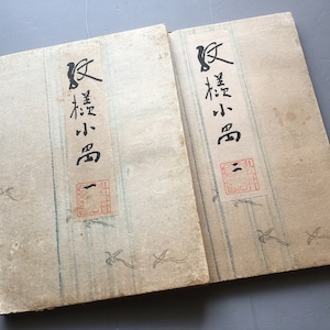 May include: Two antique Japanese books with brown covers and blue and white striped pages. The covers have black calligraphy that reads "小鳥" which translates to "small bird".
