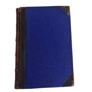 Puede incluir: Un libro antiguo de tapa dura con una cubierta azul oscuro y una encuadernaci&oacute;n y bordes de cuero marr&oacute;n.